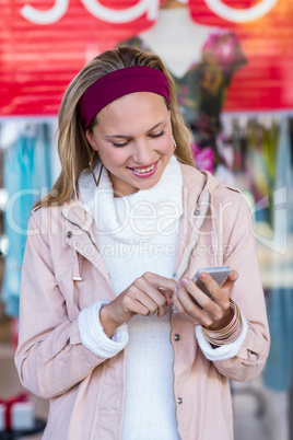 Smiling woman using smartphone in front of window