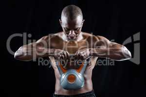 Muscular man looking down while exercising with kettlebell