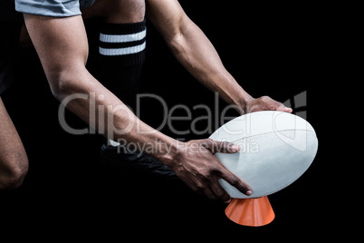 Cropped image of sportsman keeping rugby ball on kicking tee