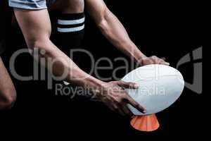 Cropped image of sportsman keeping rugby ball on kicking tee
