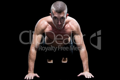 Portrait of fit shirtless athlete doing push ups