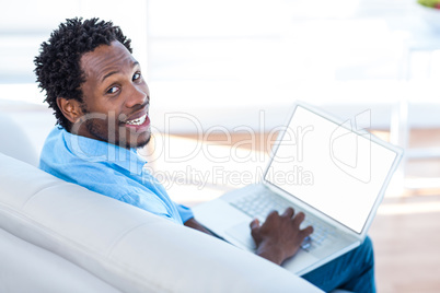 Portrait of smiling man using laptop while sitting