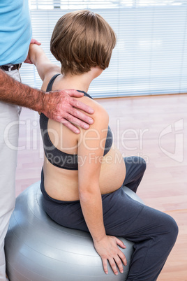 Therapist giving treatment to pregnant woman sitting