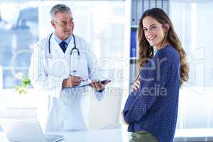 Portrait of smiling pregnant woman with male doctor in clinic