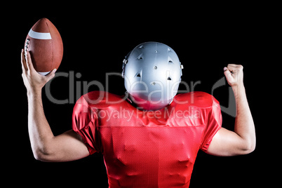 Rear view of American football player cheering while holding bal