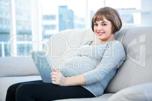 Portrait of smiling pregnant woman using digital tablet