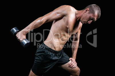 Shirtless athlete working out with dumbbell