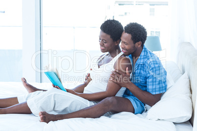 Husband and wife reading book on bed