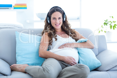 Happy pregnant woman listening music at home