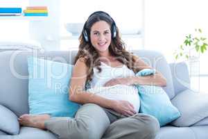 Happy pregnant woman listening music at home