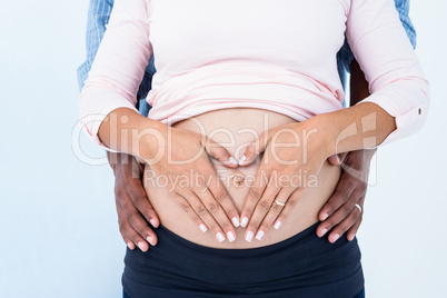 Midsection of couple hands on pregnant belly against white backg