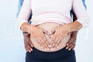 Midsection of couple hands on pregnant belly against white backg