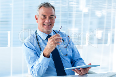 Smiling male doctor holding tablet computer in clinic