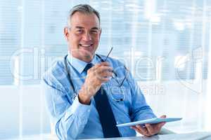 Smiling male doctor holding tablet computer in clinic