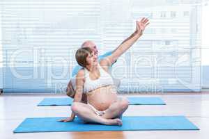 Instructor teaching yoga to pregnant woman