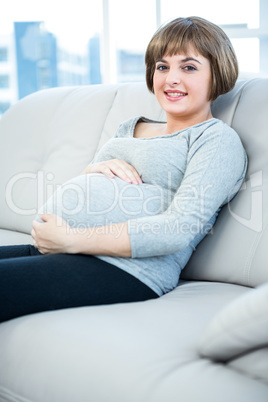 Portrait of smiling pregnant woman sitting at home