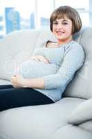 Portrait of smiling pregnant woman sitting at home