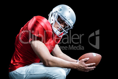 Portrait of American football player crouching while holding bal