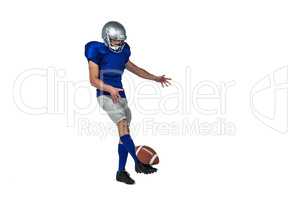 Full length American football player kicking ball
