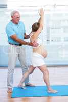 Male yoga teacher instructing pregnant woman