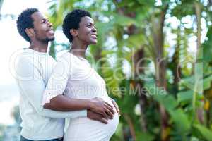 Happy man embracing wife while standing