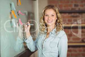 Smiling businesswoman holding marker in office