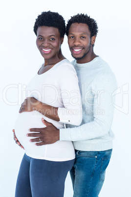 Portrait of man hugging his pregnant wife while standing