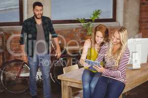 Businesswoman using tablet while male colleague looking at them