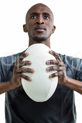 Cropped image of sportsman pressing rugby ball while looking up