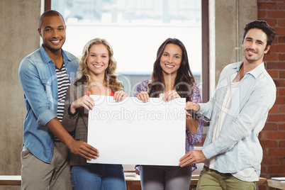 Portrait of business people holding billboard in office