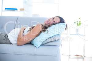 Happy pregnant woman lying on sofa