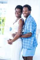Portrait of smiling husband embracing pregnant woman