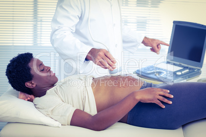 Doctor applying ultrasound gel on belly of woman