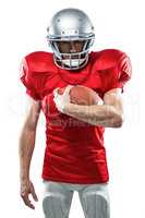 Portrait of serious American football player in red jersey holdi