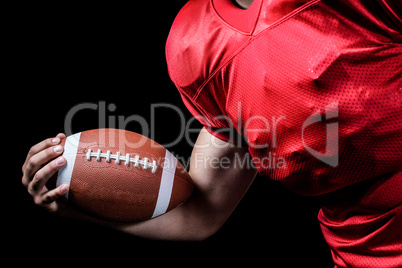 Cropped American football player holding ball