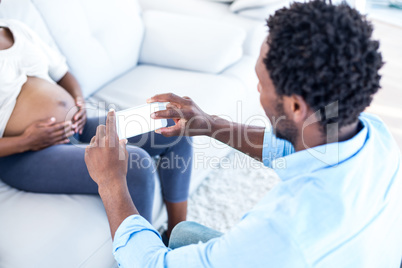 Husband photographing pregnant woman at home