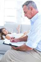 Therapist writing on notepad with female patient