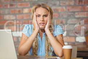 Portrait of frustrated woman sitting in front of her notebook