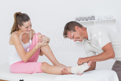Doctor bandaging his patient ankle