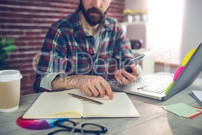 Editor looking at notepad while using smartphone