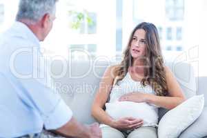 Preganant woman talking with therapist at home