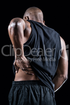 Rear view of muscular athlete suffering through back pain