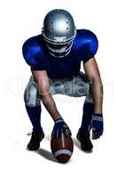 American football player holding ball while crouching