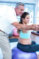 Male instructor giving exercising training to pregnant woman