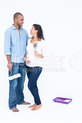 Happy couple with roller and paintbrush looking at each other