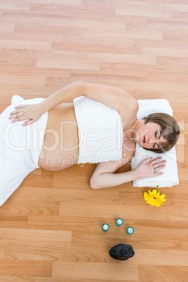 Pregnant woman with eyes closed lying on hardwood floor