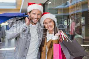 Young happy couple holding shopping bags with christmas hats on