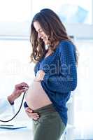 Cropped image of doctor examining pregnant woman belly in clinic