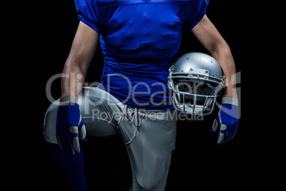 Mid section of sportsman holding helmet