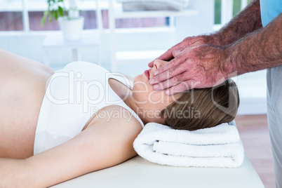 Male therapist performing reiki over eyes of woman